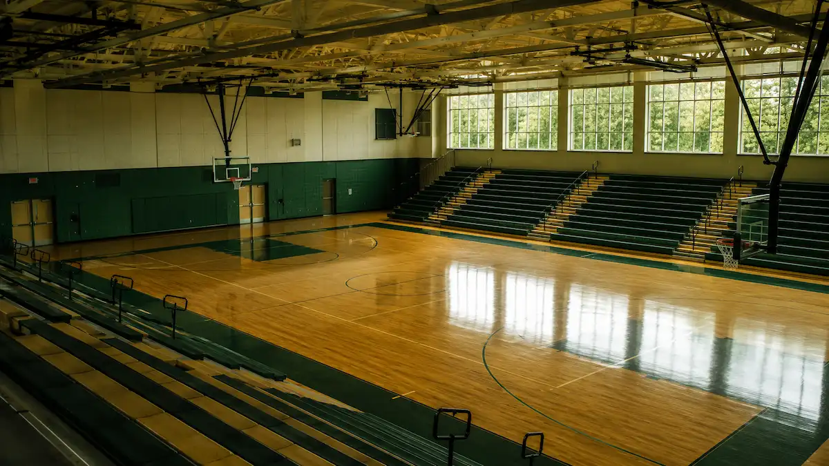 Empty college gymnasium interior with natural light through high windows